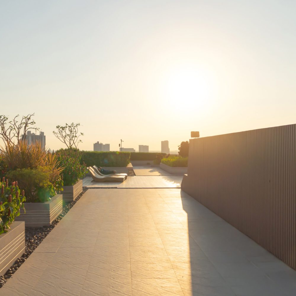 Sky garden on private rooftop of condominium or hotel, high rise architecture building with tree, grass field, and blue sky.